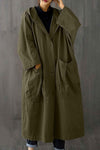 A person stands wearing the Army Green One Size Fits All Oversized Waterproof Windbreaker Jacket from looselyboho. The stylish, olive-green hooded coat features large front pockets and covers most of their body. They have one hand touching the hood and the other in a pocket, against a plain gray background.