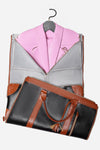 A black and brown leather garment bag, "The Smart No-Wrinkle Foldable Travel Bag Pink," crafted by The Windbreaker Jacket from waterproof PU leather, is open, revealing a pink blazer on a grey hanger inside. This sophisticated foldable travel bag features a zipper closure and tan straps with a tassel accessory. The image is taken against a white background.