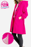 A person is wearing The WJacket's Water Resistant Oversized Hooded Windbreaker Rain Jacket in bright pink, featuring large buttons and pockets. The coat is a "Barbara Pink Limited Edition." An inset image reveals the interior lining of the jacket, showcasing a pink and white checkered pattern that highlights its timeless style and versatility.